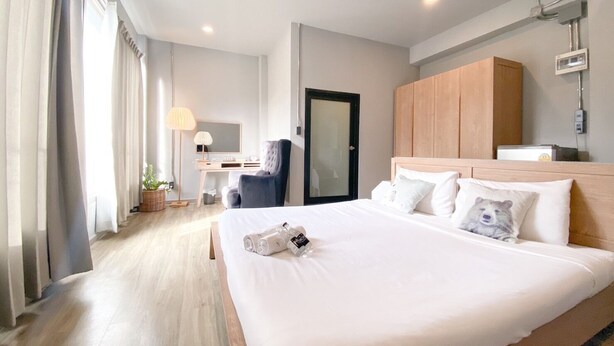 Habitación de hotel con una cama grande, un escritorio con silla, un armario y la puerta del baño.