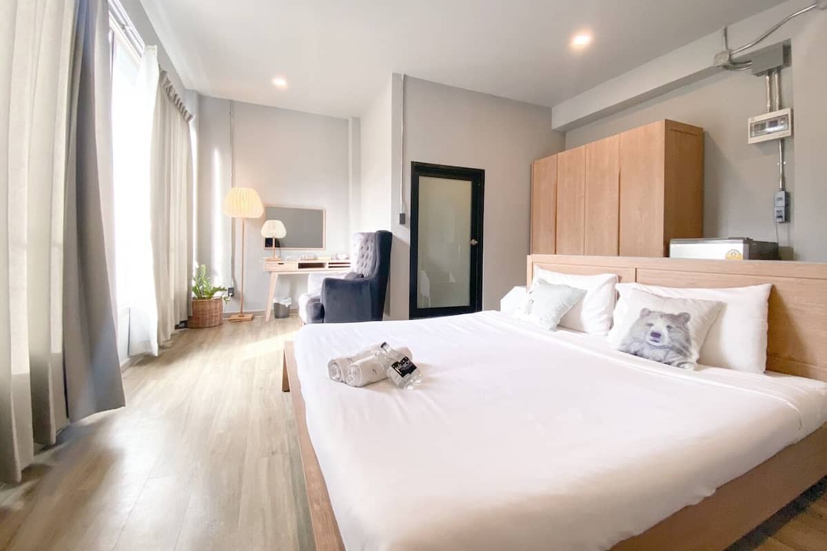 Une chambre d’hôtel avec un grand lit, un bureau avec une chaise, une armoire et une porte de salle de bain.