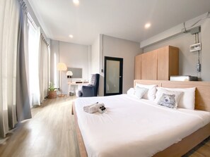 Une chambre d’hôtel avec un grand lit, un bureau avec une chaise, une armoire et une porte de salle de bain.