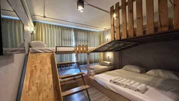 Ein Schlafraum mit Etagenbett, Holzlade, Schreibtisch und Spiegel.