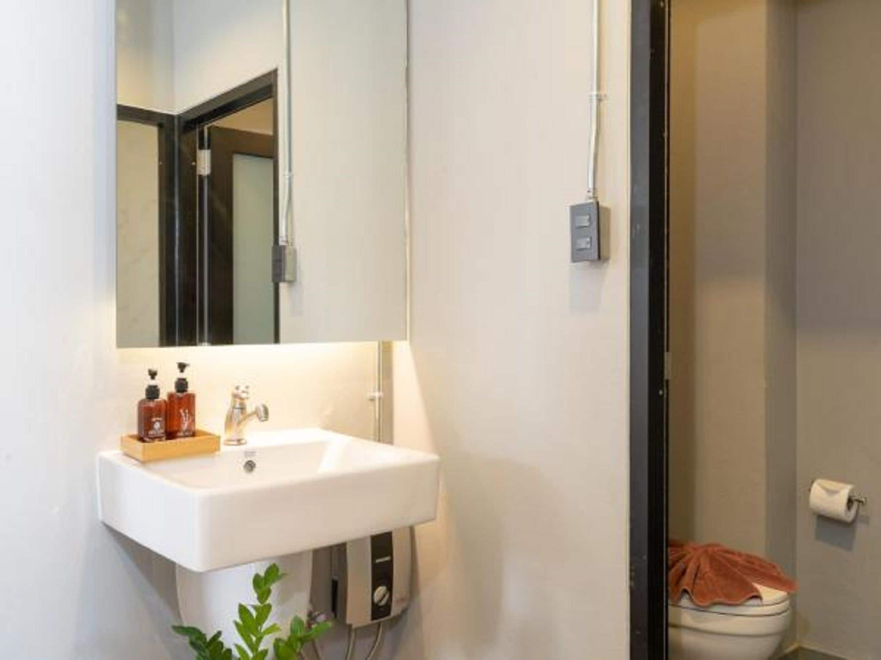 A bathroom with a white sink, a mirror, a towel rack, and a toilet.