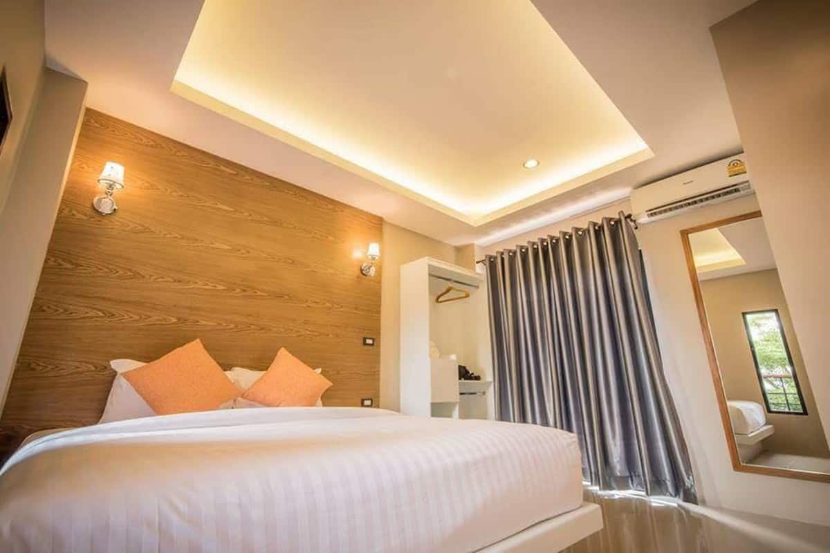 A modern hotel room with a large bed, wooden headboard, and a ceiling light.