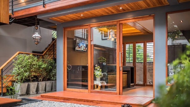 A modern house with a wooden staircase, a glass door entrance, and a small garden area. - Le Terrarium Hotel (Chiang Rai)