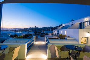 A rooftop terrace with outdoor seating, a view of the sea, and modern architecture. - Spanelis Hotel (Mykonos)