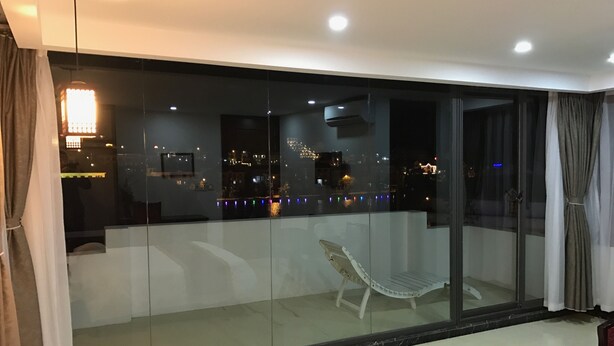 A modern room with a large sliding glass door leading to a balcony. The room has a minimalist design with a white bed, a small table, and a chair. - Sapa Memory Hotel (Sa Pa)
