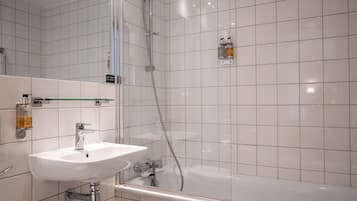 A modern bathroom with a white sink, a glass shower enclosure, and a bathtub.