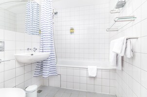 A bathroom with a white sink, a bathtub, and a shower curtain.