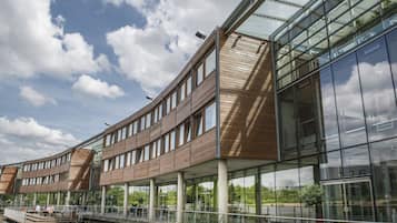 A modern building with a curved wooden facade, large glass windows, and a waterfront view.