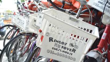 A row of bicycles with attached baskets labeled "Ringo's Foyer Guest-House."