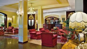 A lobby with red armchairs, a chandelier, and a reception desk. - Hotel Salus Terme (Abano Terme)