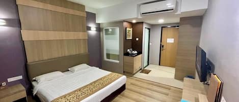 A hotel room with a bed, bedside table, wardrobe, and a television.