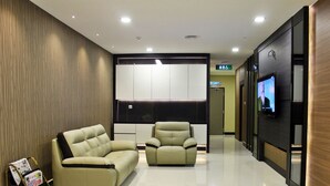 Una sala de estar moderna con un sofá y un sillón, un televisor de pantalla plana montado en la pared y una pared de acento de madera.