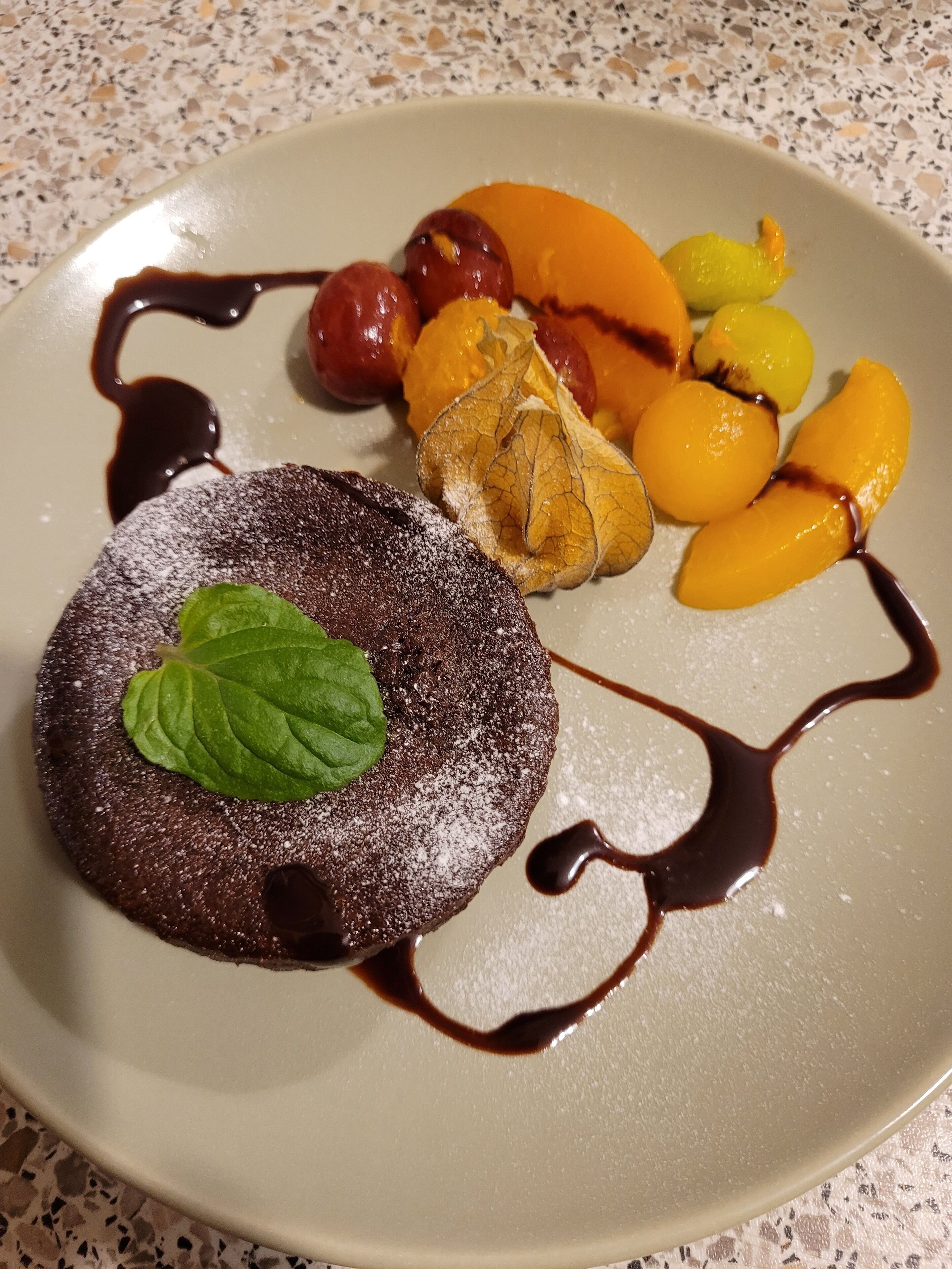 Ein Dessertteller mit Schokoladenkuchen, Früchten und Schokoladensauce.