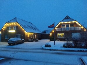 Una casa de dos pisos con tejado cubierto de nieve, un balcón y una bandera.