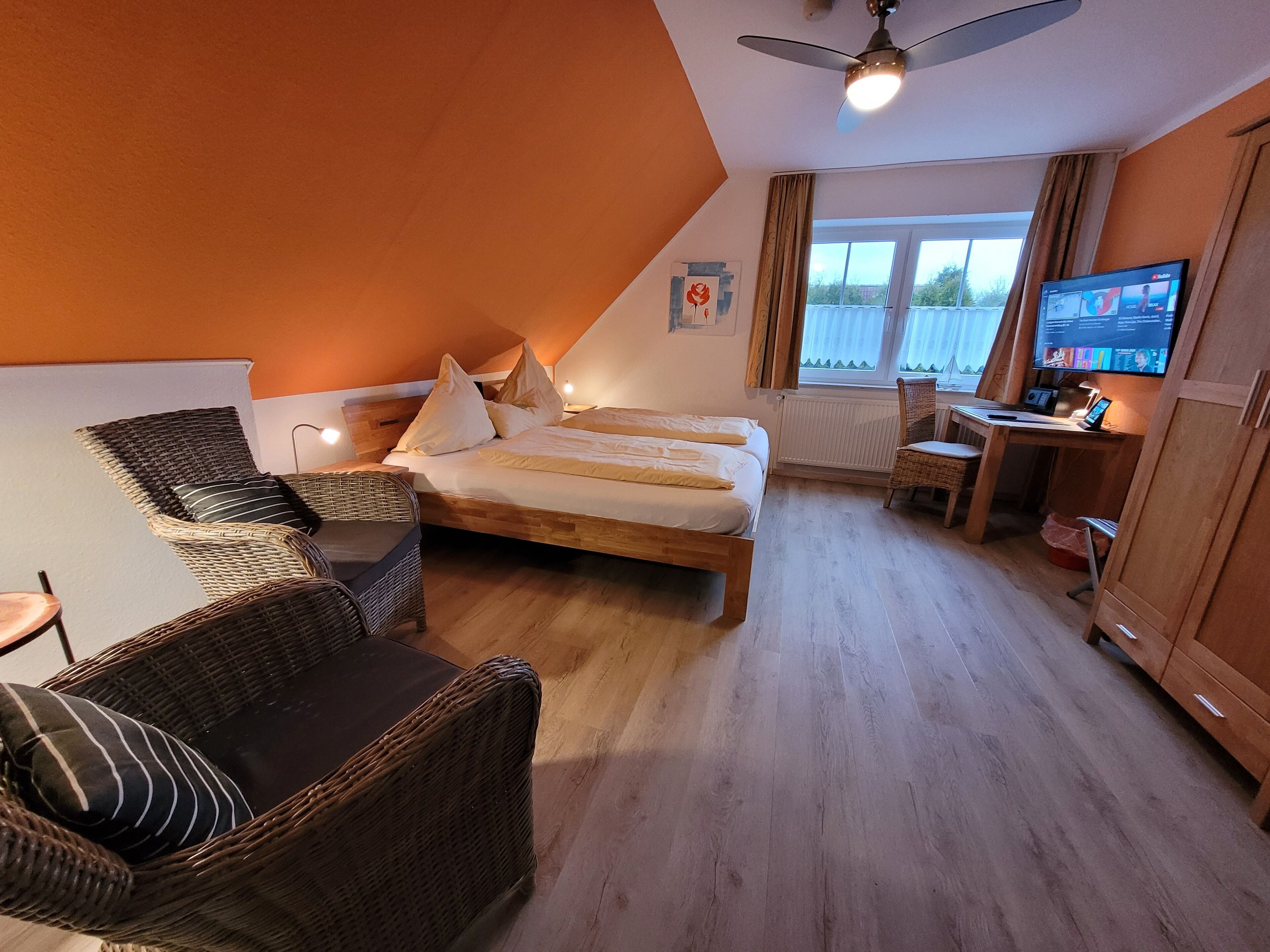 Una camera da letto con un letto, due sedie, una scrivania e una televisione.