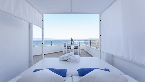 Ein Balkon mit Bett, weißen Vorhängen und Meerblick.