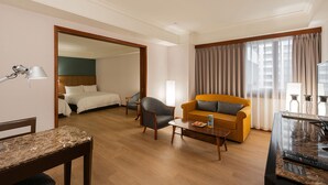 Una habitación de hotel con cama, sofá, mesa de centro y mesa de comedor.
