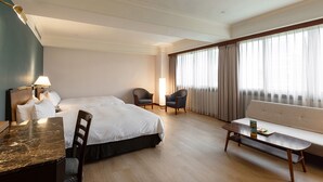 Una habitación de hotel con cama, escritorio, silla, sofá y mesa de centro.
