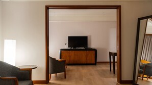 Una sala de estar con un aparador de madera, un televisor y dos sillones estampados.