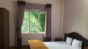 A bedroom with a bed, a nightstand, a wardrobe, and a window with curtains. - Noi Bai Hotel (Hanoi)