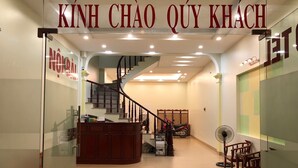 A reception area with a staircase, a reception desk, and a fan. - Noi Bai Hotel (Hanoi)