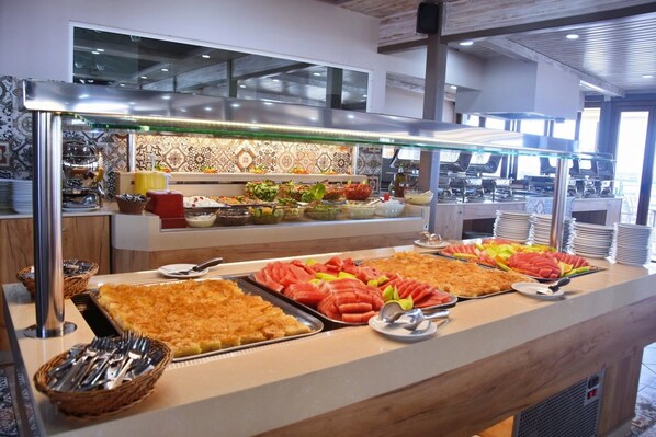 A buffet with various food items and utensils. - Kalia Beach (Hersonissos)