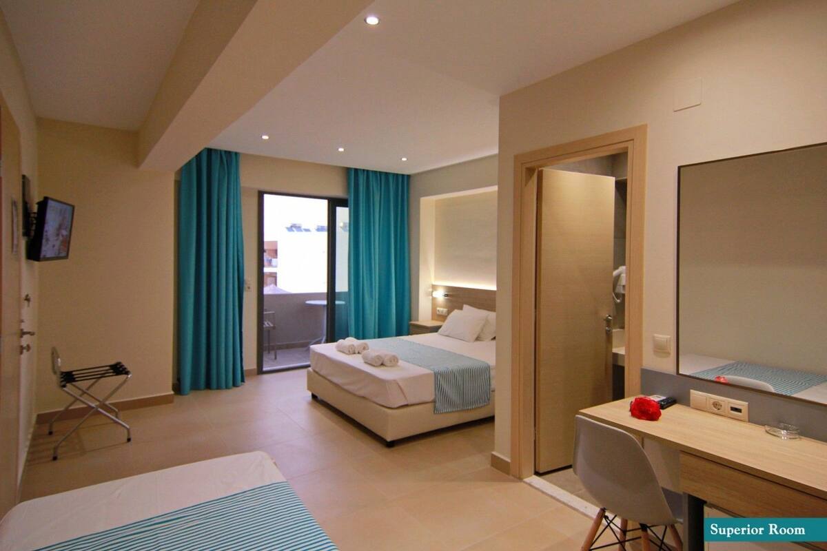 Ein Hotelzimmer mit einem Bett, einem Schreibtisch, einem Sessel, einem Spiegel und einem Fernseher.