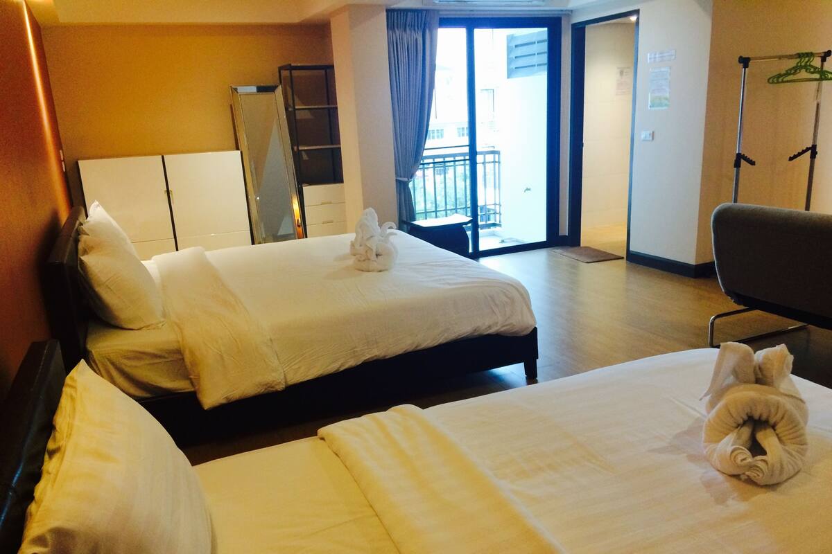 Une chambre d’hôtel avec deux lits, une armoire, un miroir, une chaise et une vue sur le balcon.