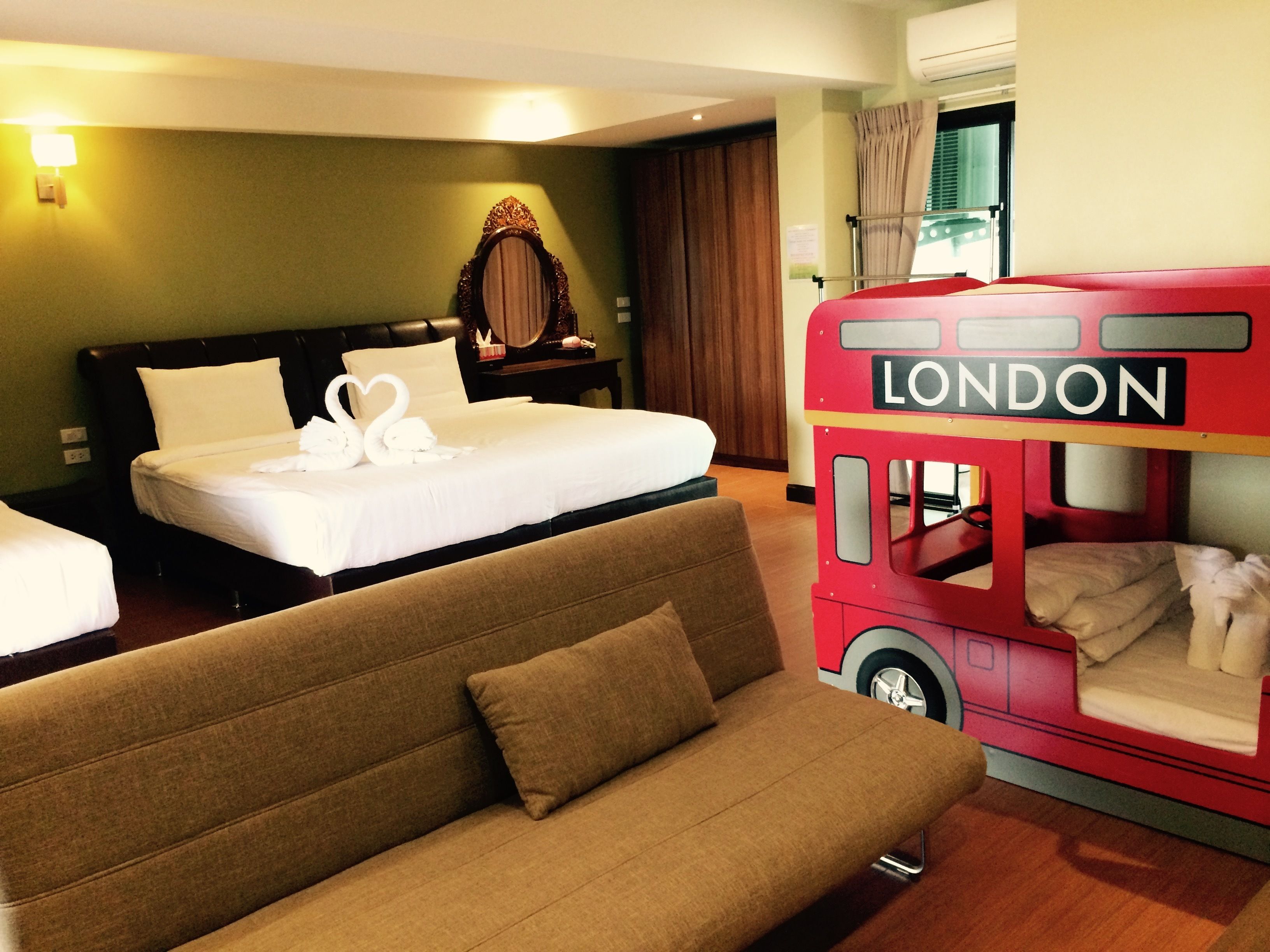 A hotel room with a bed, a sofa, and a red London-themed bunk bed.