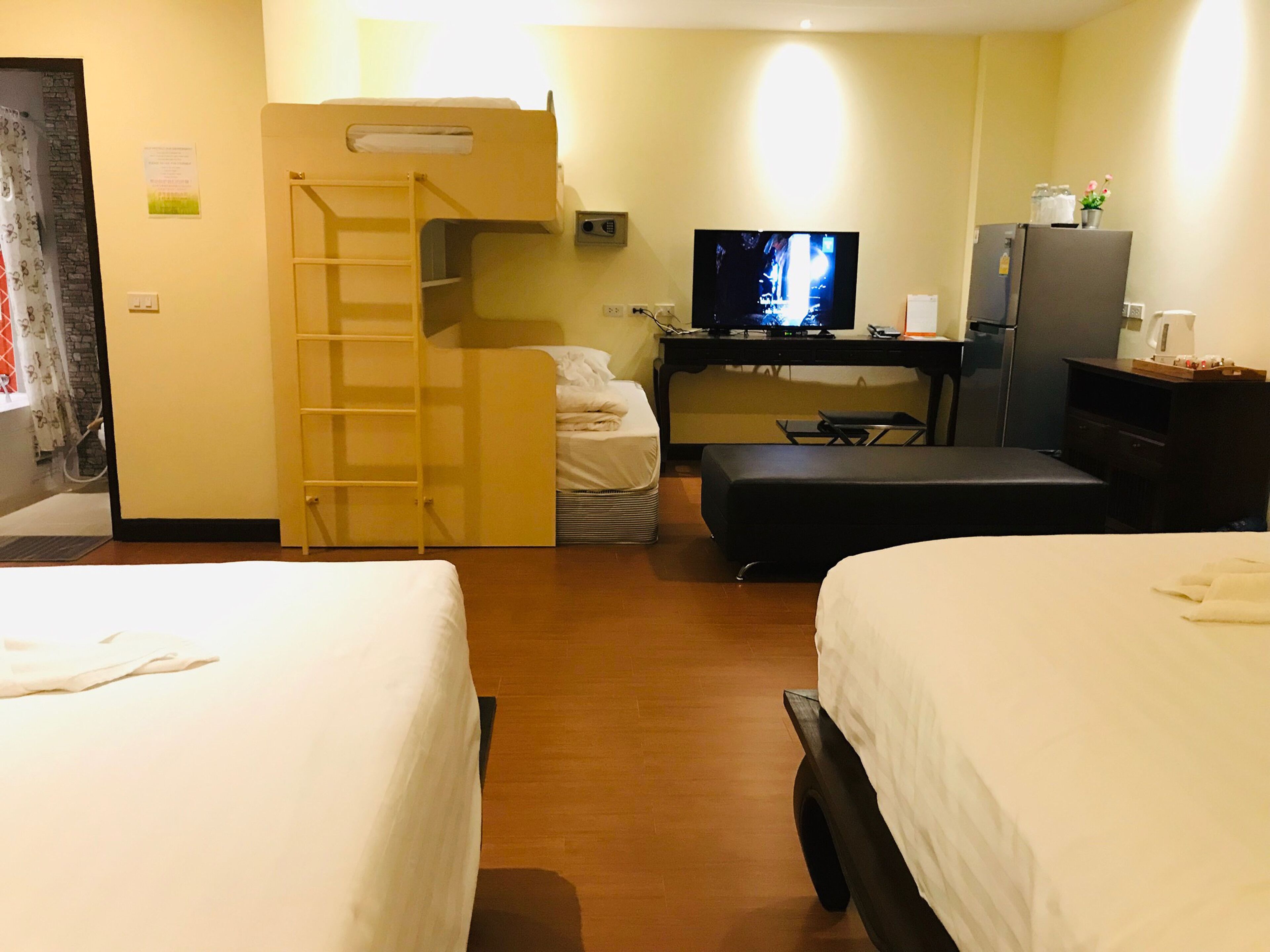 A hotel room with two beds, a TV, a desk, and a wardrobe.