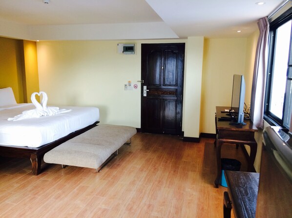 A hotel room with a bed, a bench, a desk, and a door.