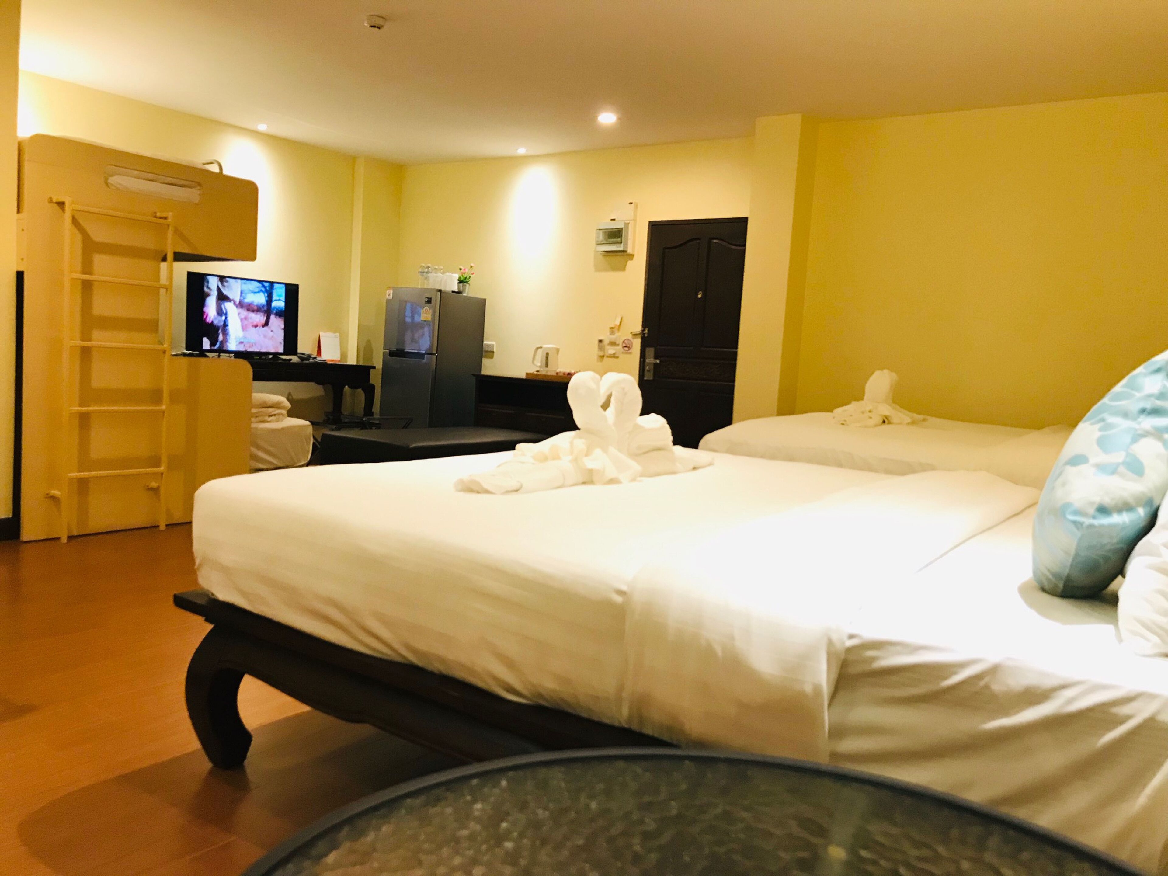 Habitación de hotel con dos camas, televisión, refrigerador, escritorio y baño.