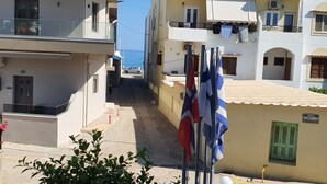 A narrow street with buildings on either side, balconies with clothes hanging, and flags. - Zannis Hotel (Rethymno)