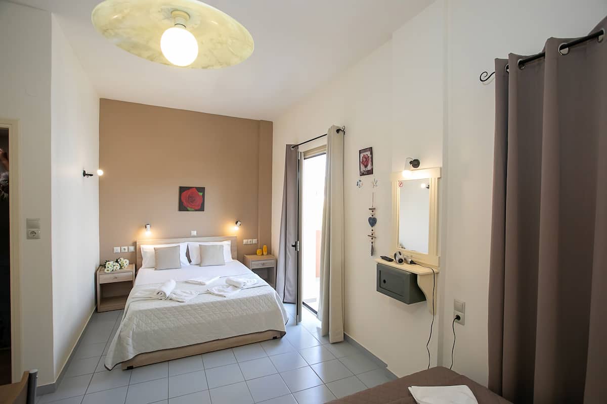 Habitación de hotel con cama, mesitas de noche, espejo y zona de ducha.