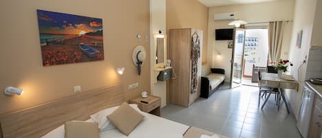 Habitación de hotel con cama, escritorio, silla, espejo y un cuadro de una playa.
