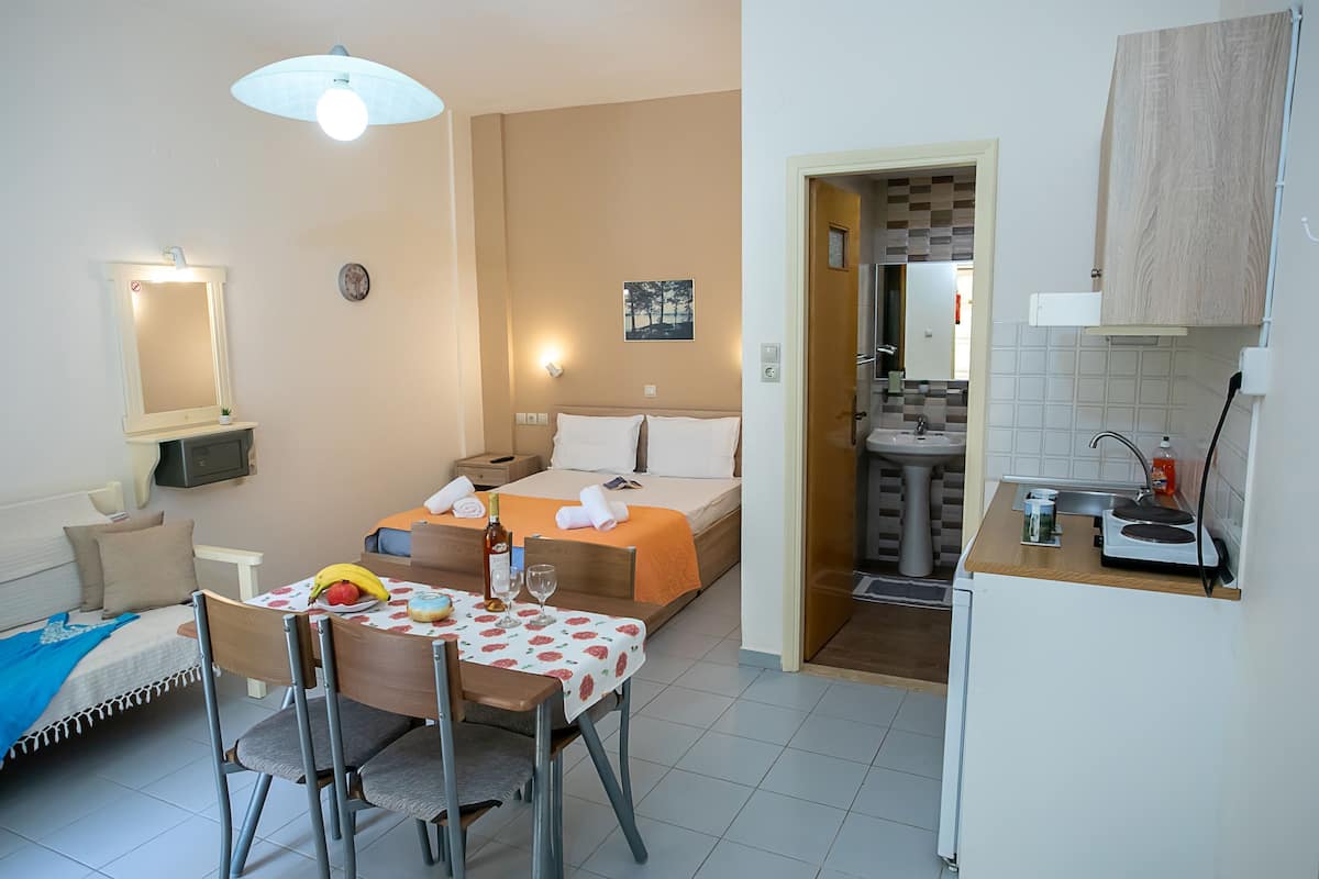 Una habitación de hotel con cama, mesita de noche y zona de comedor con mesa y sillas.