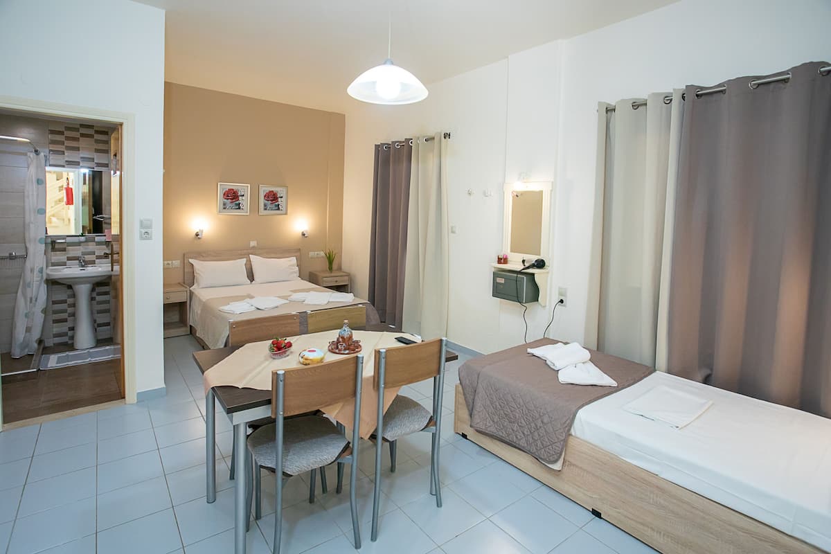 Habitación de hotel con dos camas, una mesa de comedor, sillas, baño con ducha y espejo.