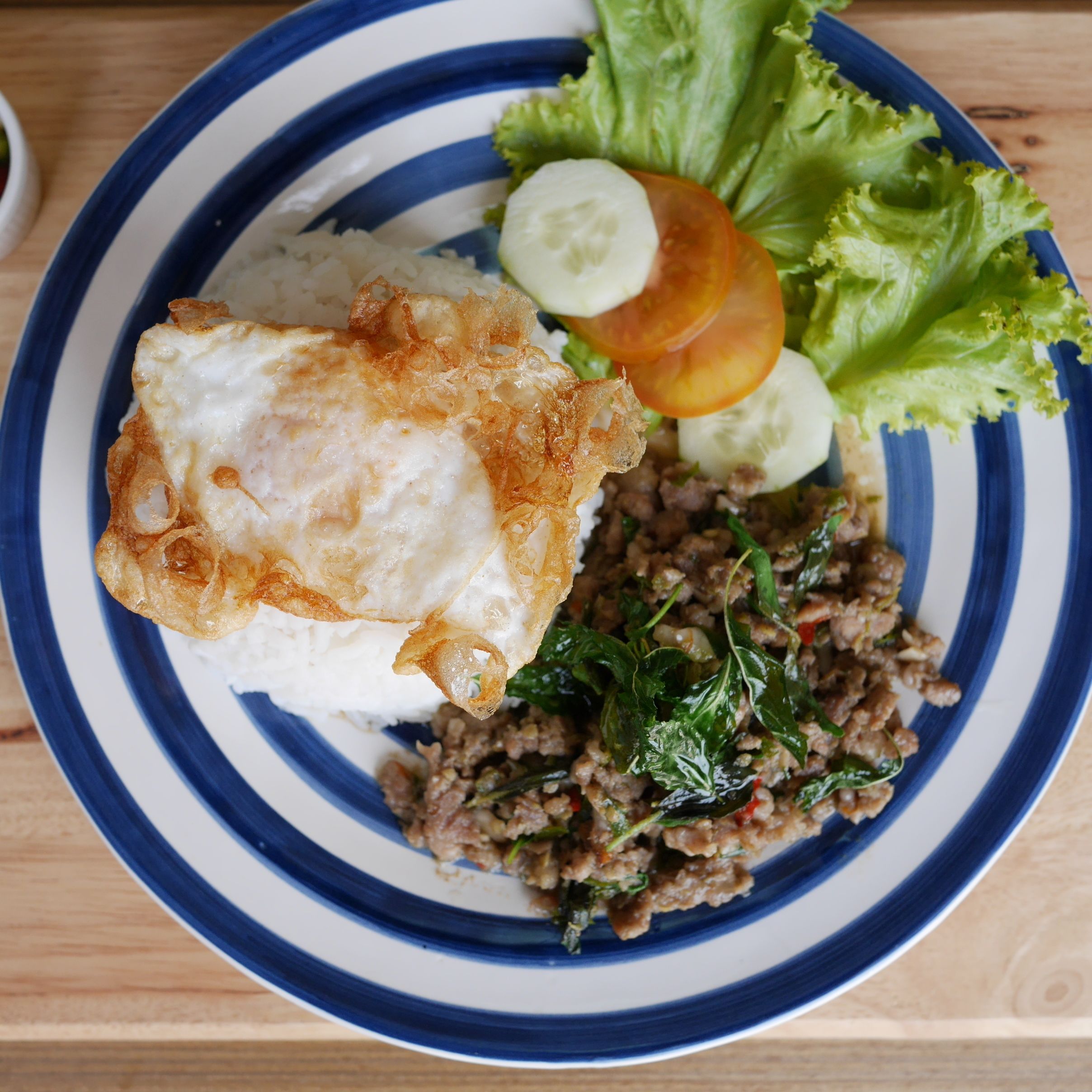 Ein Teller mit Spiegelei, Reis, Hackfleisch, Salat und Gurkenscheiben.