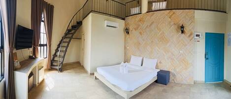 Habitación de hotel con cama, escalera, aire acondicionado instalado en la pared, puerta azul y pared con patrón de espiga.