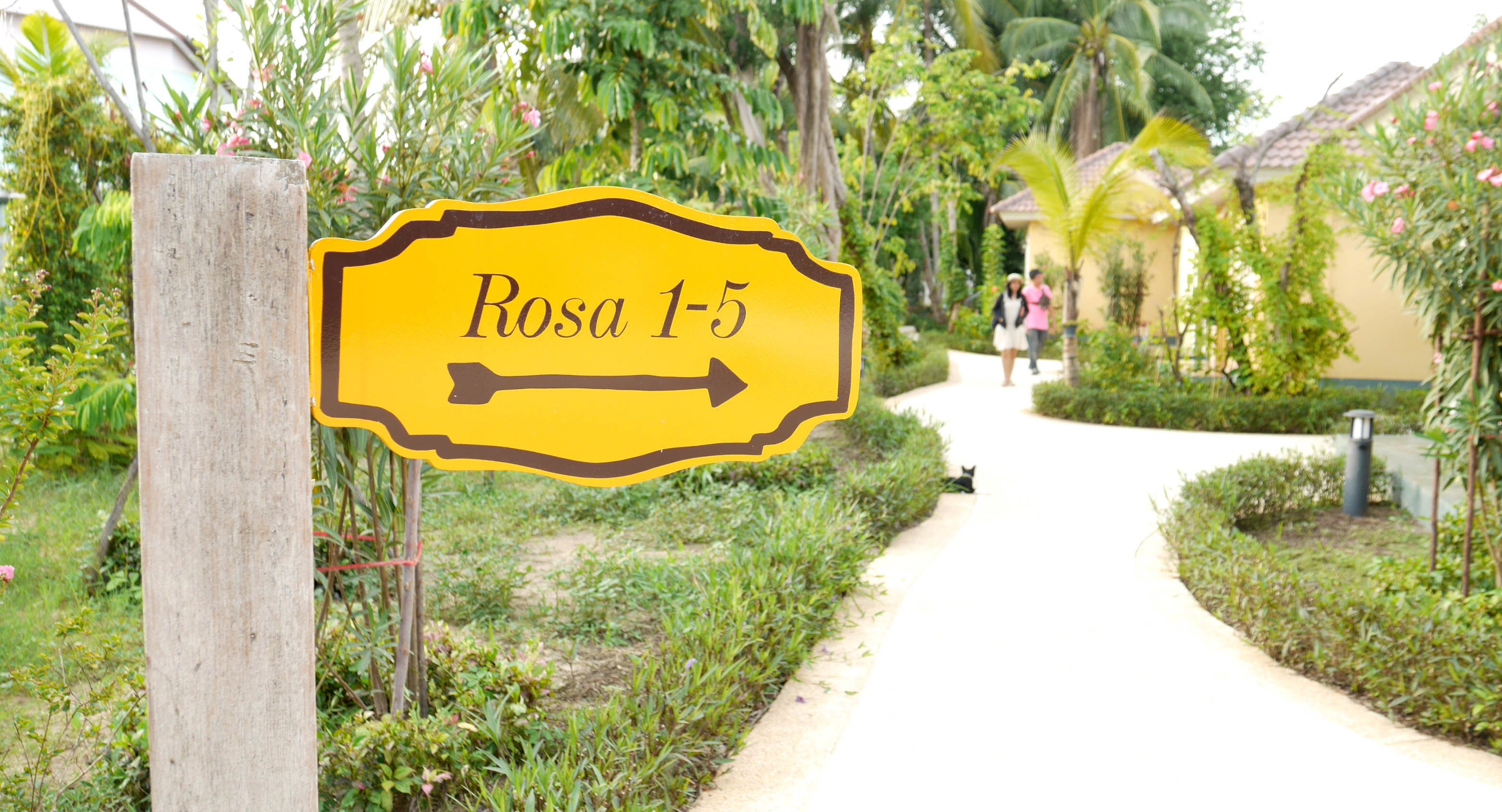 A sign indicating 'Rosa 1-5' with a pathway leading to a building.
