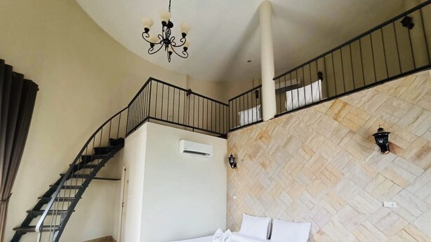 Un dormitorio con cama, una escalera, aire acondicionado de pared y una araña.