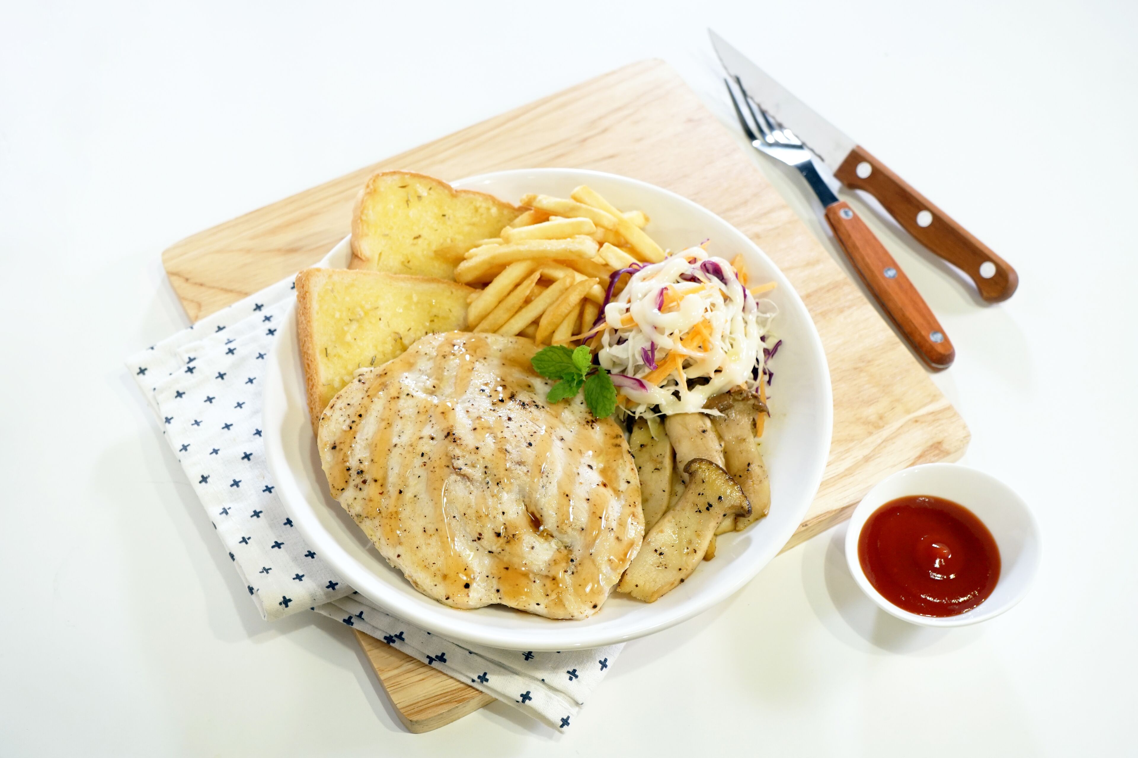 Un plato de comida con un trozo de pollo a la parrilla, papas fritas, ensalada de col y un tazón pequeño de kétchup.