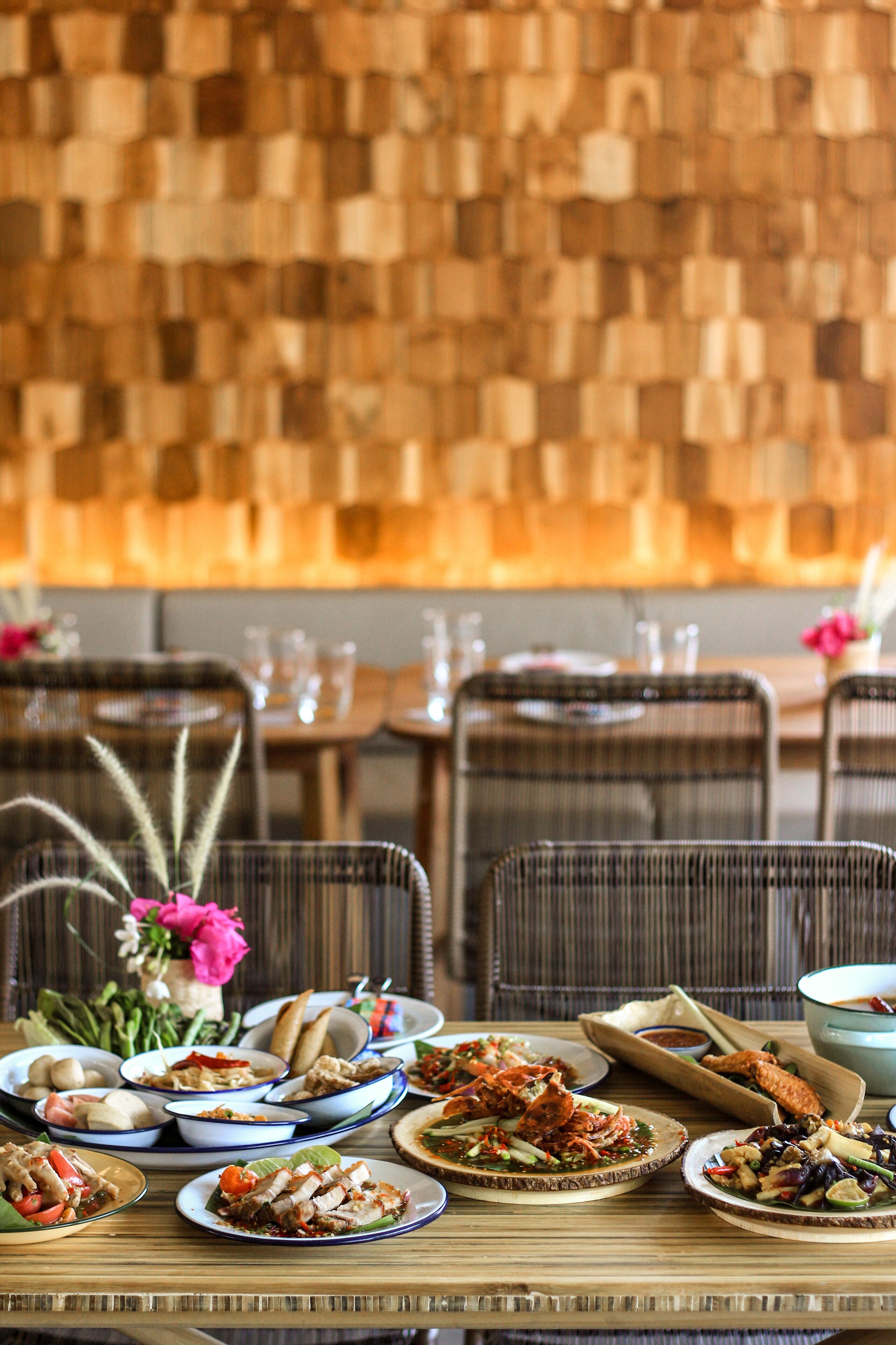 A dining table set with various dishes, a vase with flowers, and a wooden wall in the background.