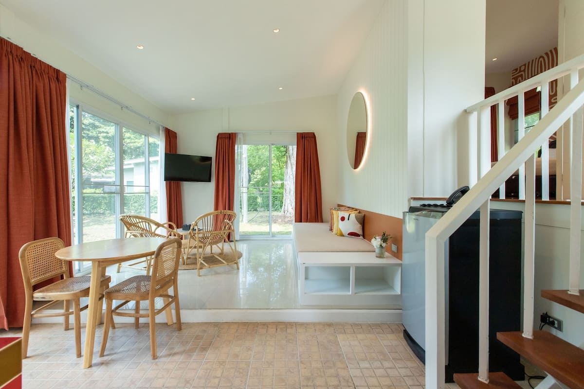 Un vaste espace de vie comprenant une table à manger, des chaises, un canapé et un escalier.