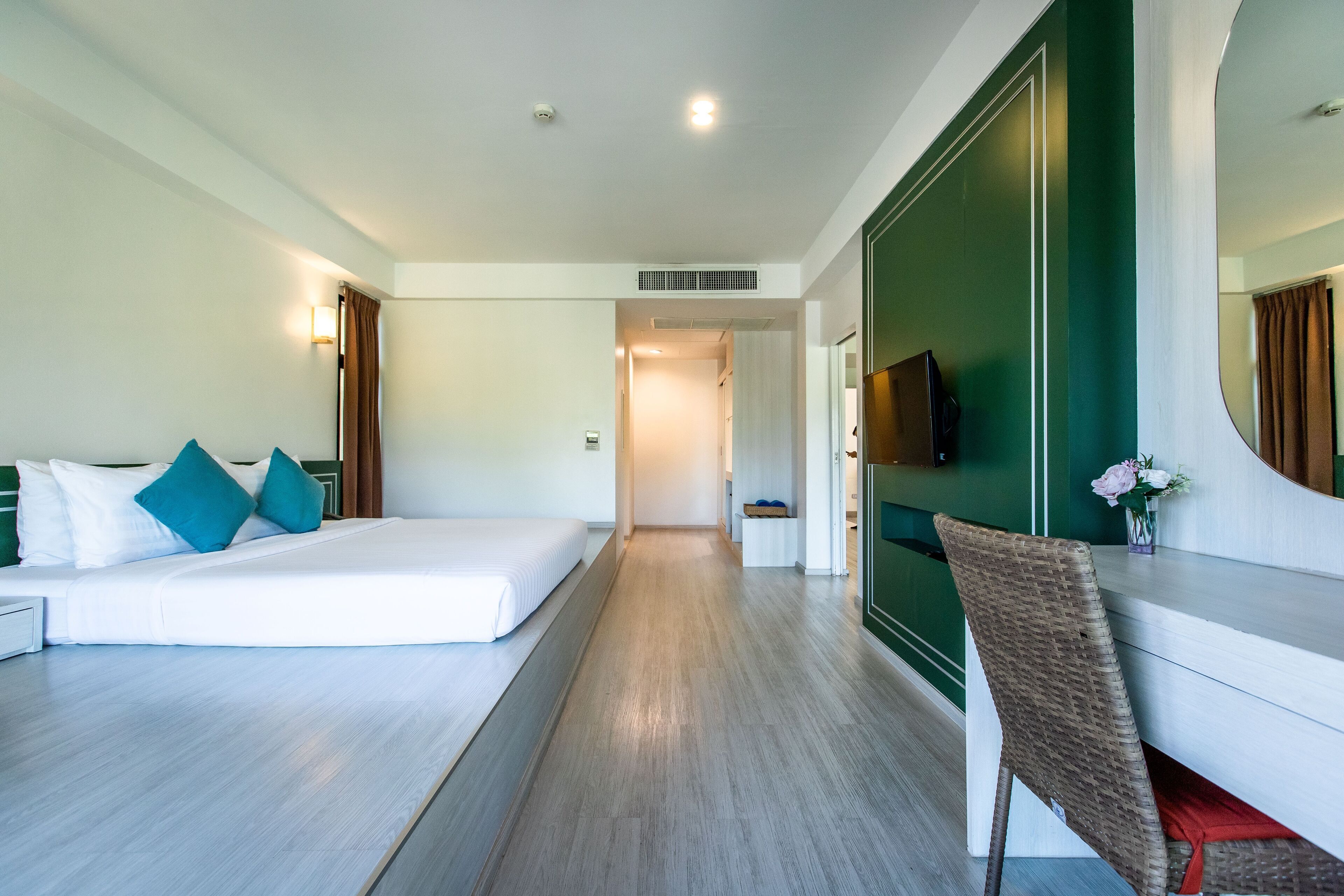 A hotel room with a bed, a chair, a desk, and a TV.