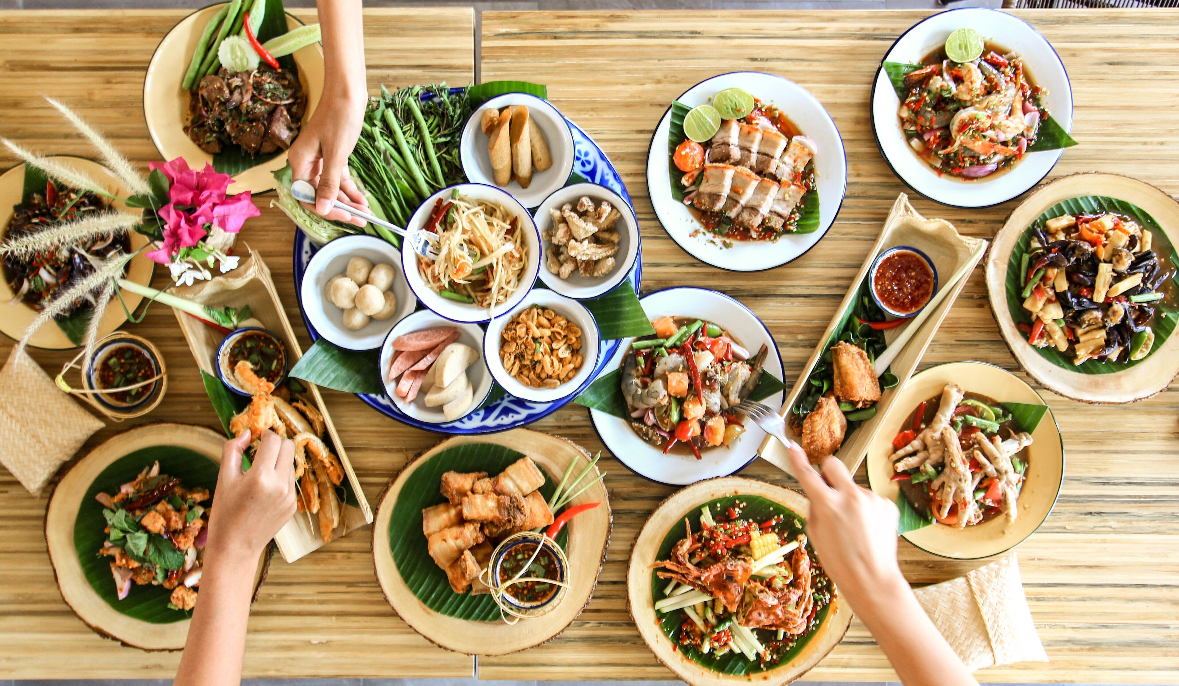 A variety of dishes arranged on a wooden table, suggesting a communal dining experience.