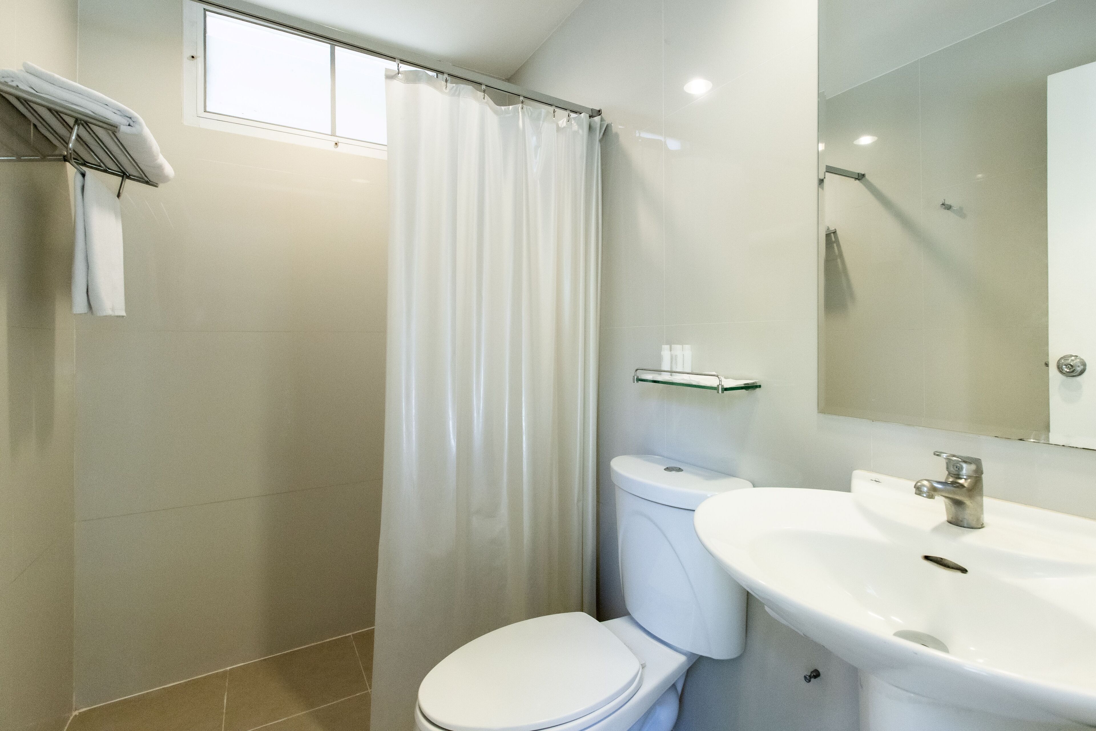 A modern bathroom with a toilet, sink, and shower curtain.