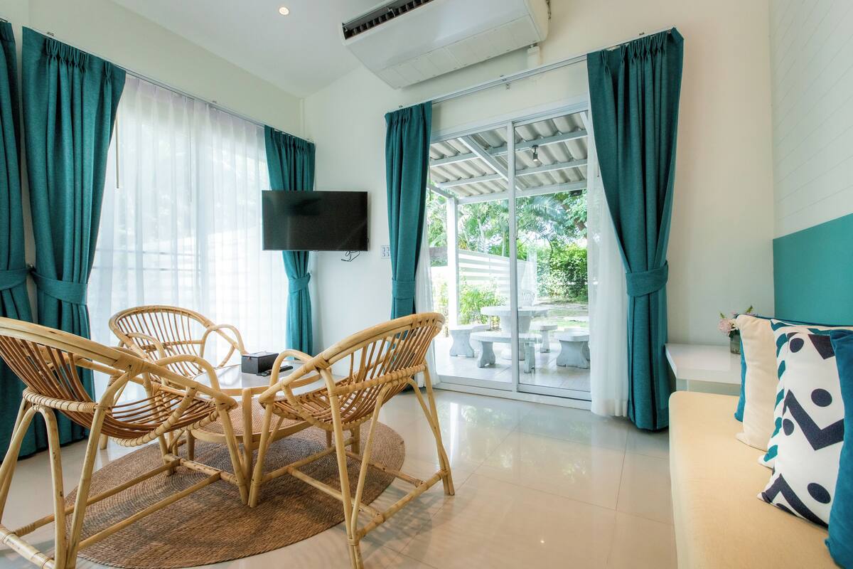 Une pièce comprenant une table et des chaises, un canapé, un téléviseur et une porte-fenêtre coulissante donnant sur un patio.