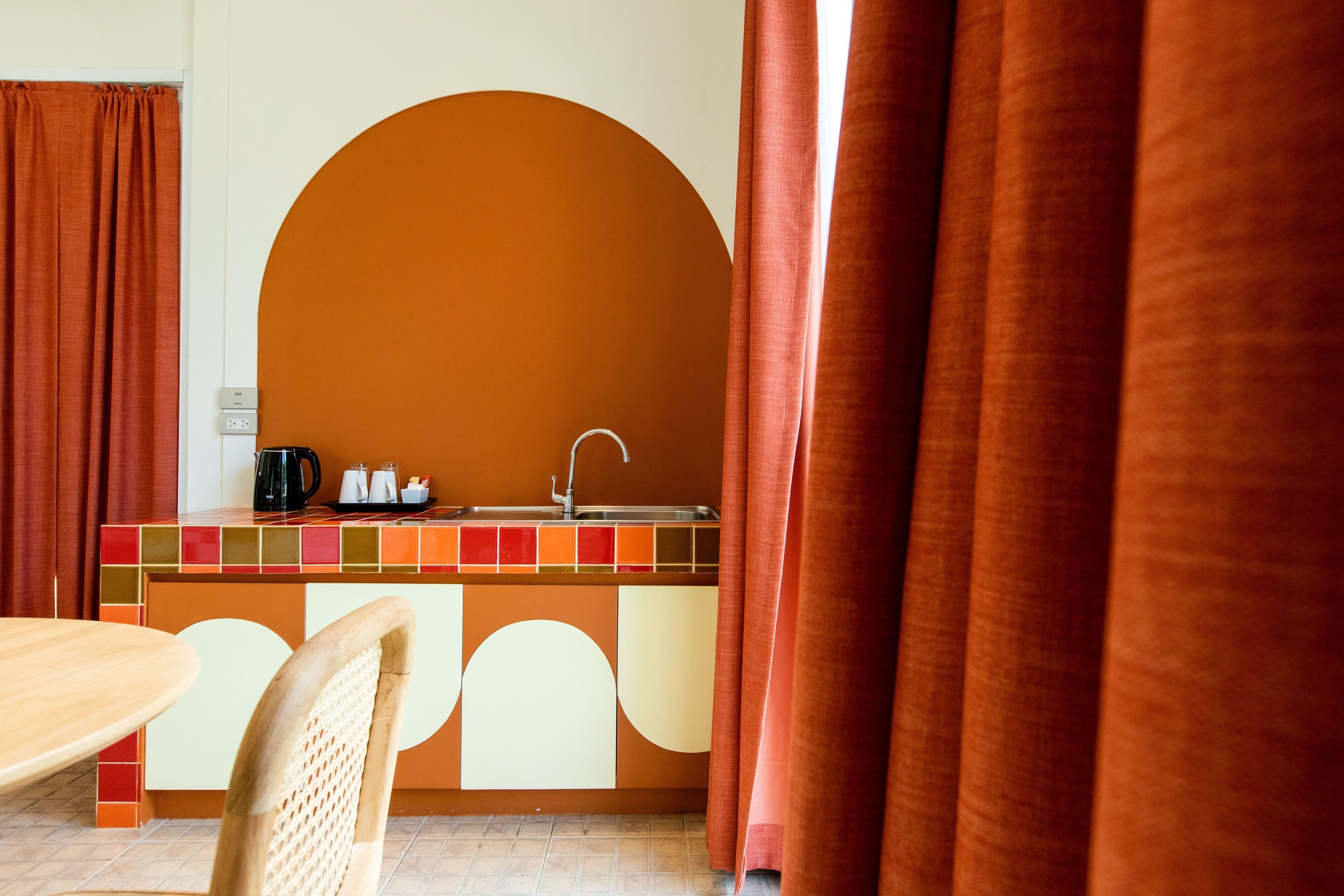 A kitchen area with a sink, a coffee maker, and a kettle on the counter.