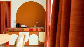 A kitchen area with a sink, a coffee maker, and a kettle on the counter.